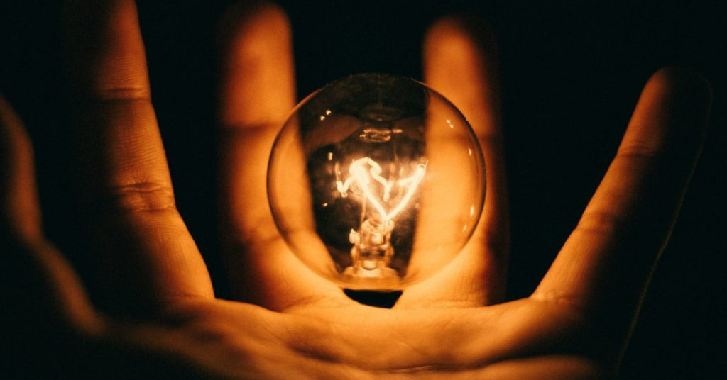 A hand holds a light bulb, signifying insight