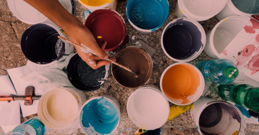 A person dips their brush in some paint