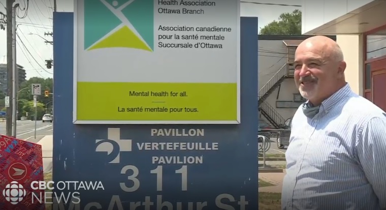 CMHA Ottawa Executive Director Tim Simboli stands in front of sign