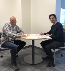 Two co-workers sit together at a work station