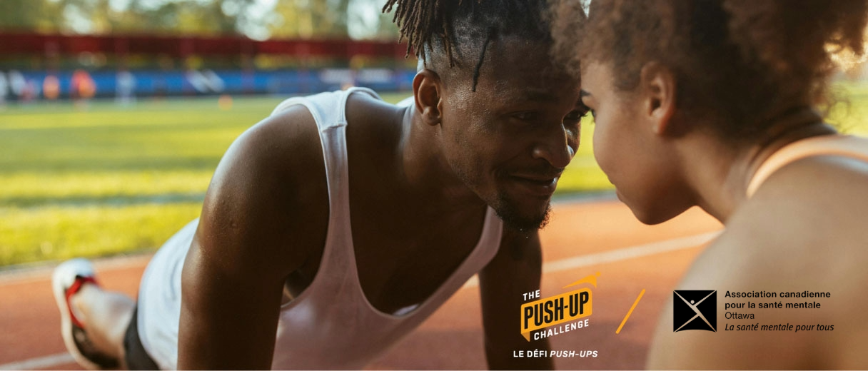 Un jeune homme et une jeune femme noirs font des pompes face à face sur une piste d'athlétisme.