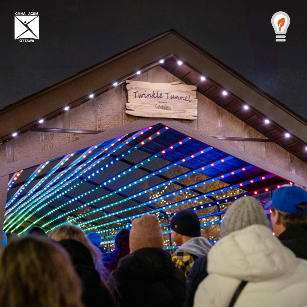 A 40-foot tunnel is lit up with colourful lights against a night sky. Several visitors enter the tunnel.

Un tunnel de 40 pieds est éclairé par des lumières colorées sur fond de ciel nocturne. Plusieurs visiteurs entrent dans le tunnel.